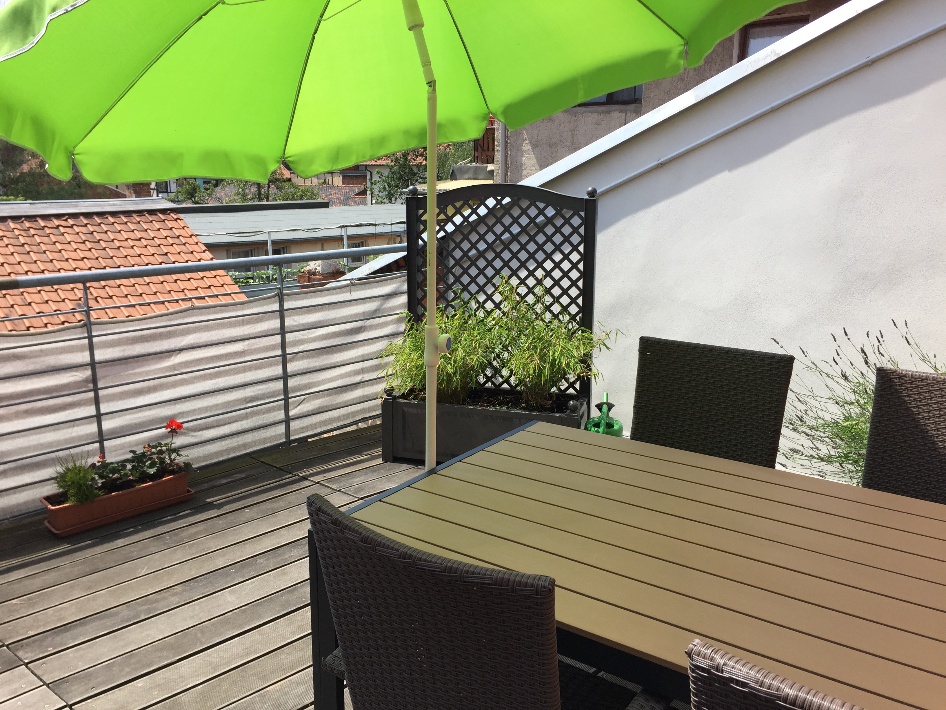 Dachterrasse mit Tisch und Stühlen, Sonnenschirm und Blumenkübeln